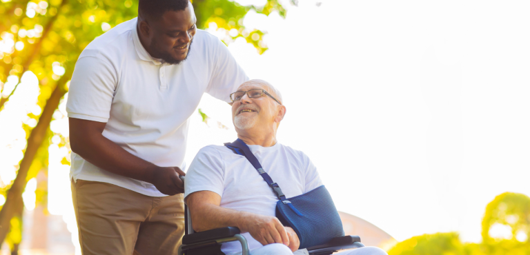adult male in wheelchair and helper transporting him