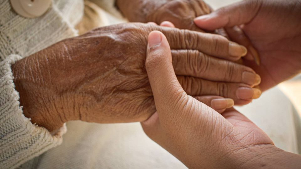 Holding hands A woman is holding an elderly woman's hand.